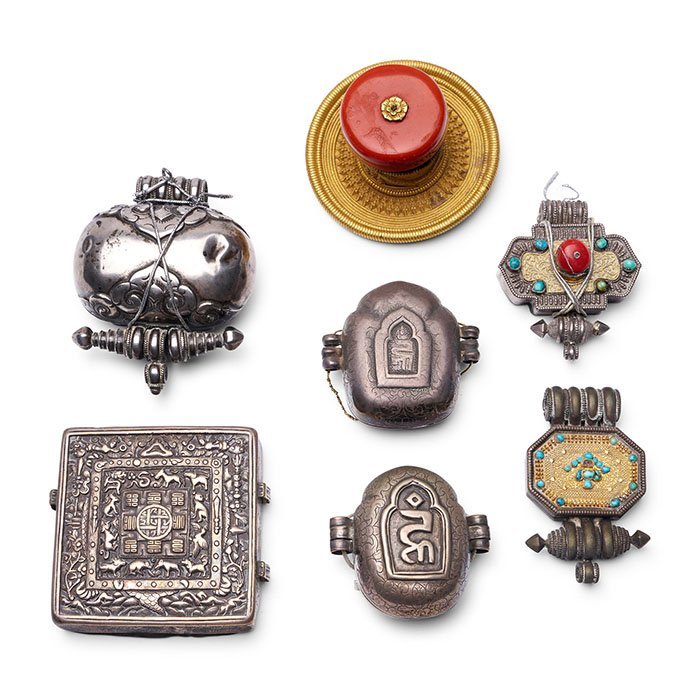 A group of seven silver repoussé amulets and a gilt copper alloy hair ornament